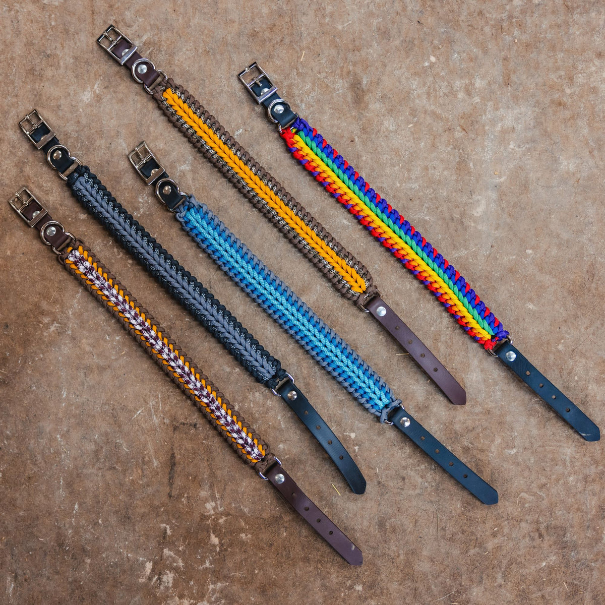 Assorted handmade paracord dog collars laid out on concrete