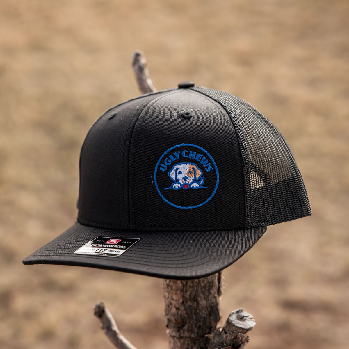 Black Ugly Chews trucker cap on a fence post